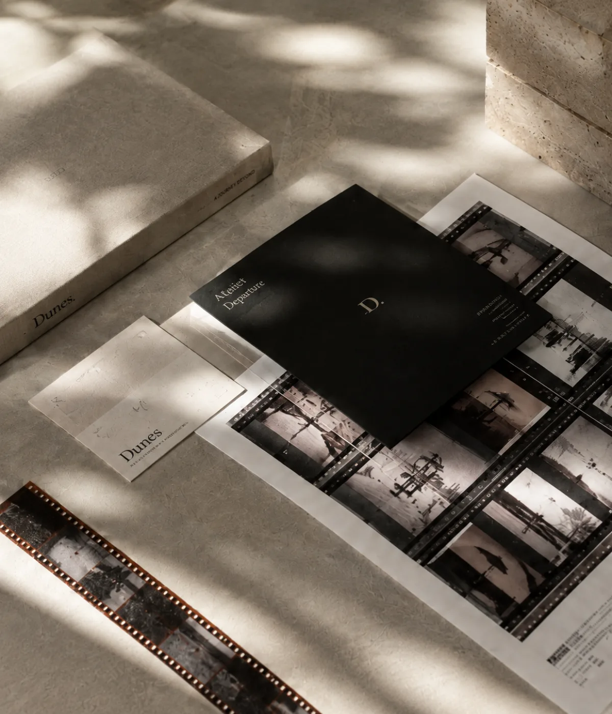 Art-directed arrangement of identity papers, a black booklet and photographic film strips in soft daylight.